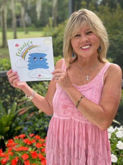 a photo of Rhonda Goodall holding her book Frizzle's Rainbow in the Clouds